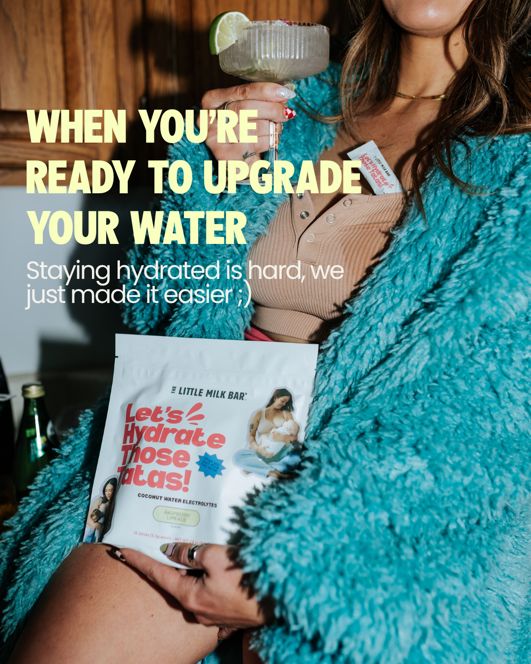 Mom holding a bag of Let's Hydrate Those Tatas coconut water electrolytes and a shaker bottle, an easy way to upgrade your water while breastfeeding